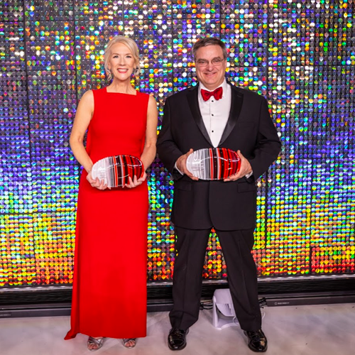 Man and woman in formal wear holding awards.